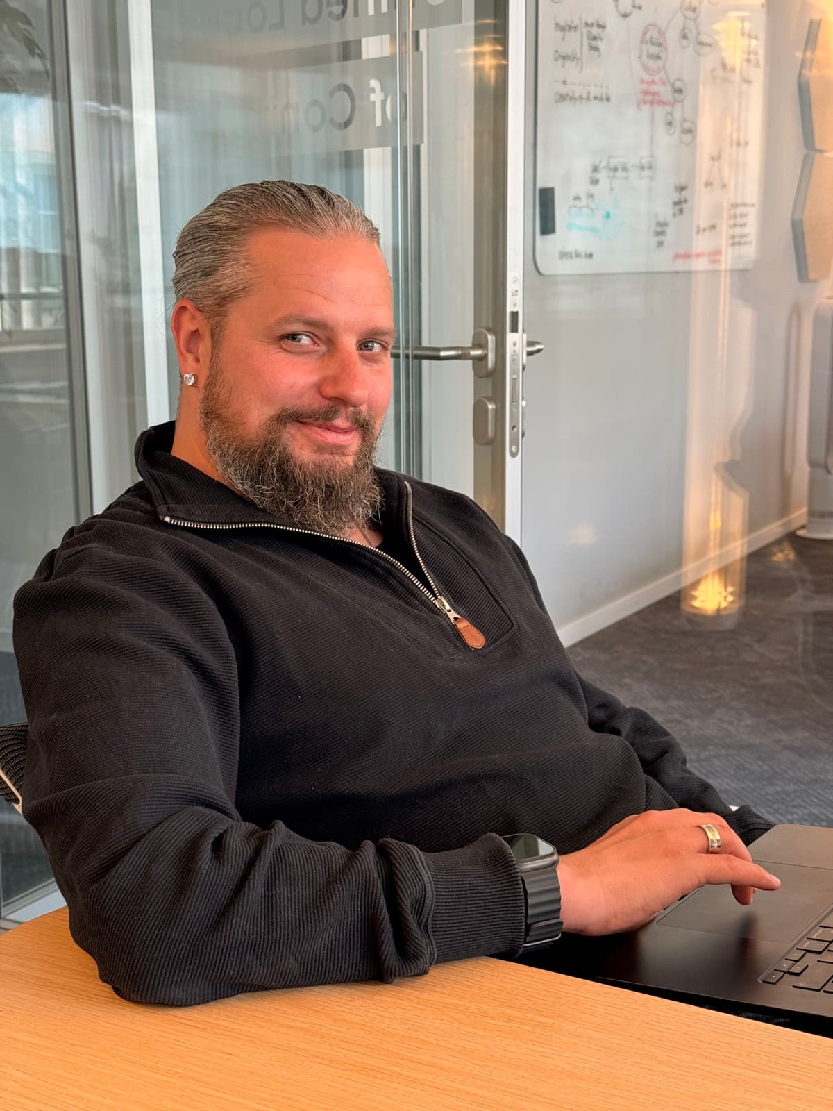 Christoph Brinke am Laptop vor einem Whiteboard mit Systemskizzen